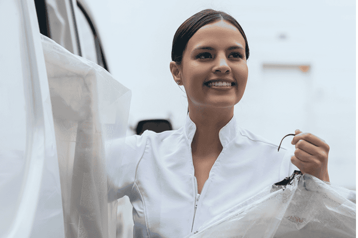 Vrouw met witte overall op een elektrische laadpaal, milieuvriendelijke elektrische auto, duurzame mobiliteit, investeren in groene energie, opuro.be.